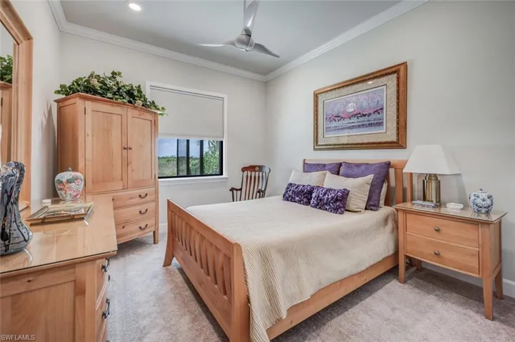 Bedroom with ceiling fan, light carpet, and ornamental molding