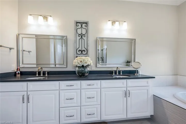 Bathroom with tiled bath and double sink vanity