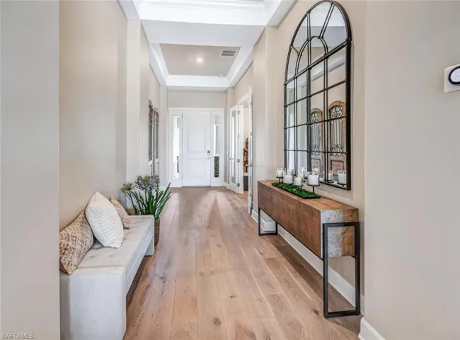 Hall featuring a tray ceiling and light wood-type flooring