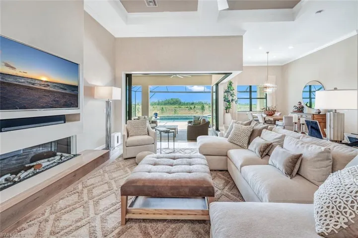 Living room featuring plenty of natural light, wood-type flooring, crown molding, and an inviting chandelier