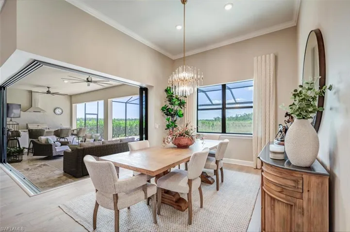 Dining area featuring ceiling fan with notable chandelier, ornamental molding, and wood-type flooring