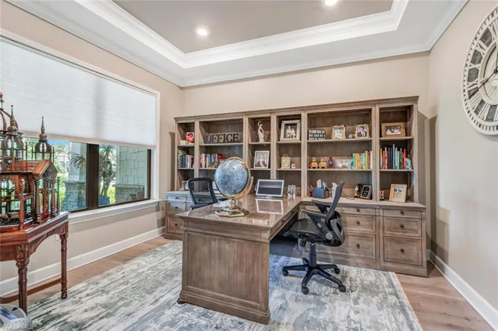 Office with a raised ceiling, ornamental molding, and light wood-type flooring