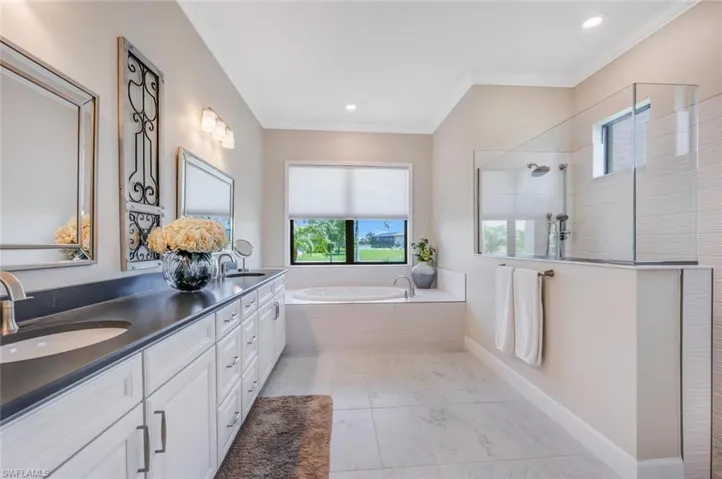 Bathroom with ornamental molding, independent shower and bath, tile flooring, and double vanity