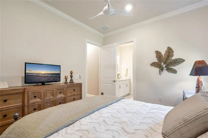 Bedroom with ornamental molding, ensuite bathroom, and ceiling fan