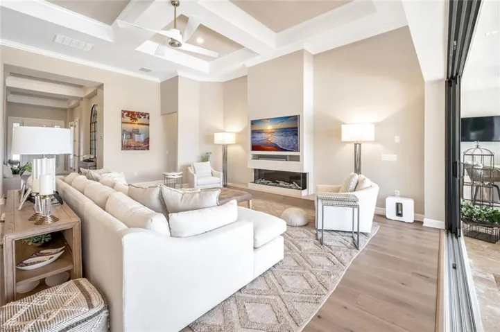 Living room featuring crown molding, hardwood / wood-style flooring, coffered ceiling, and ceiling fan