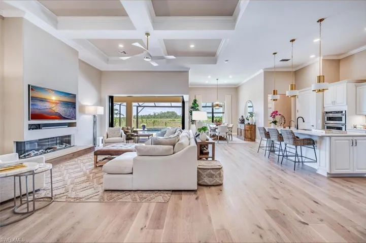 Living room with coffered ceiling, light hardwood / wood-style flooring, and crown molding
