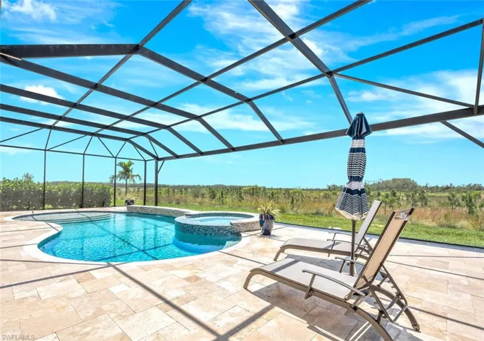 View of pool featuring a patio area, glass enclosure, and an in ground hot tub