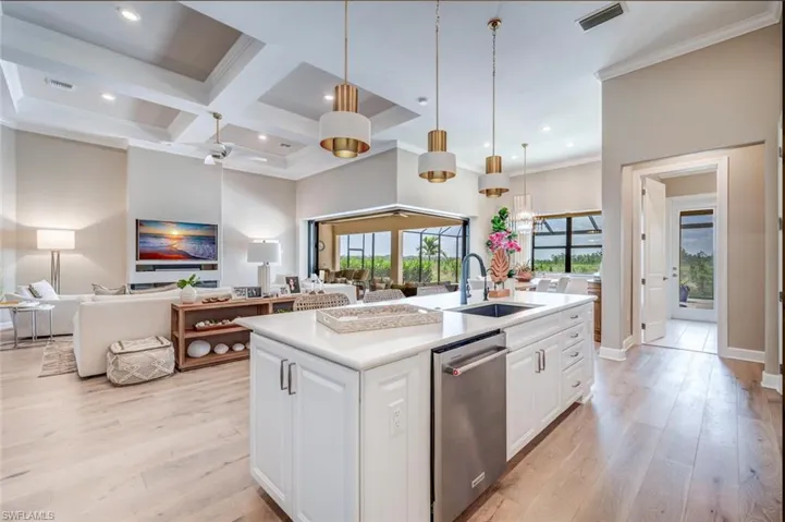 Kitchen with an island with sink, coffered ceiling, white cabinets, and stainless steel dishwasher