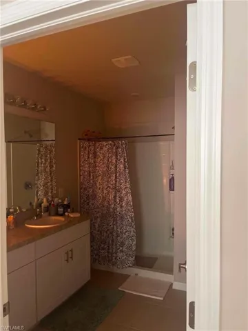 Bathroom featuring a vanity with an integrated sink, a large mirror, and a shower-tub combination with an enclosure