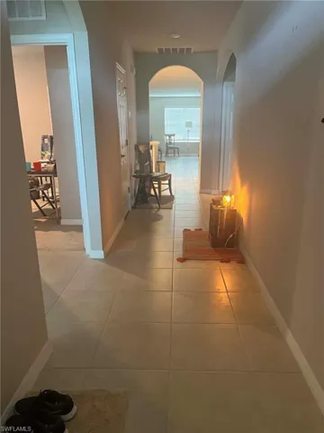 Hallway featuring neutral-toned tile flooring and arched doorways