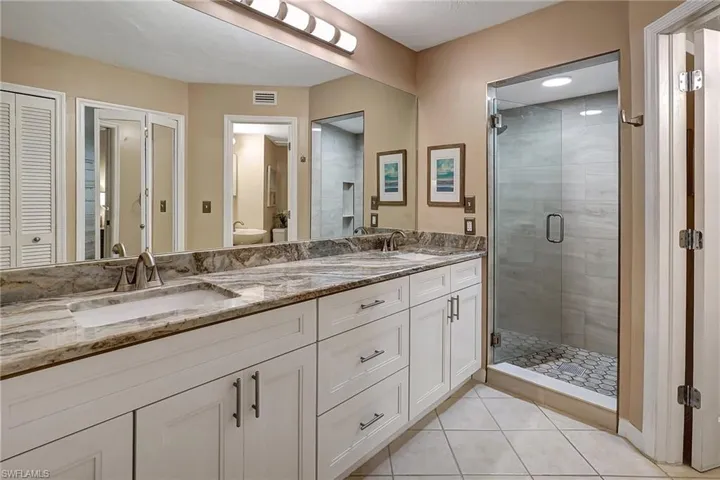 Bathroom with tile patterned floors, vanity, and an enclosed shower