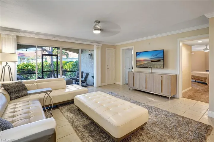 Tiled living room with ceiling fan and crown molding