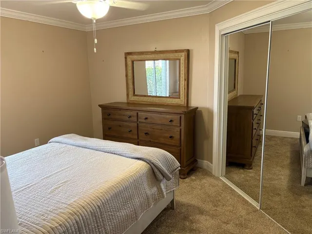 Bedroom featuring baseboards, a closet, light colored carpet, and crown molding