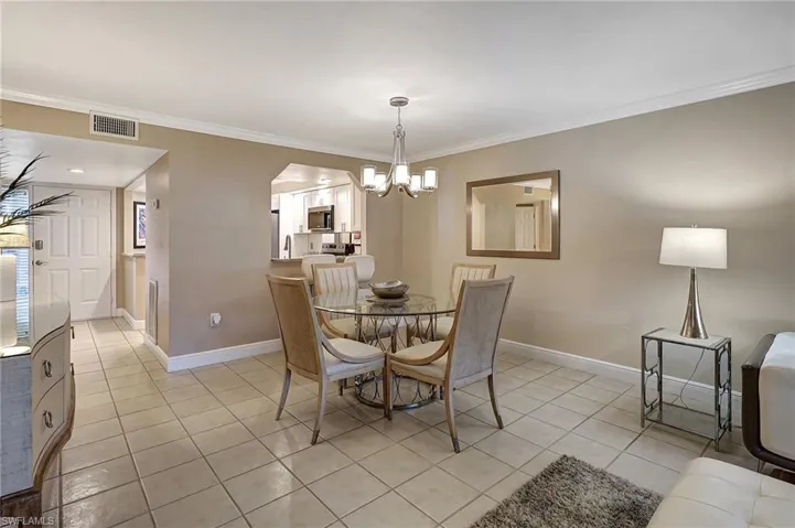 Dining space featuring light tile patterned floors, an inviting chandelier, and ornamental molding