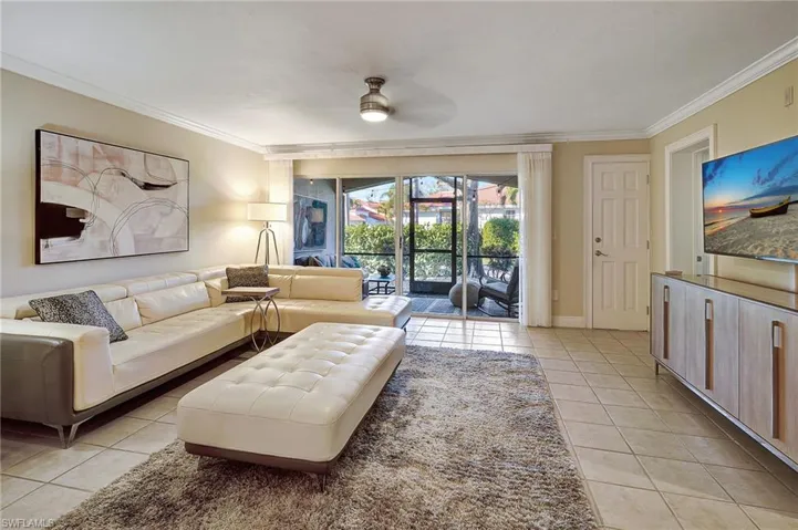 Living room featuring ceiling fan, light tile patterned flooring, and ornamental molding