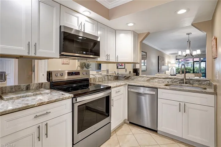 Kitchen with sink, crown molding, a notable chandelier, white cabinetry, and stainless steel appliances