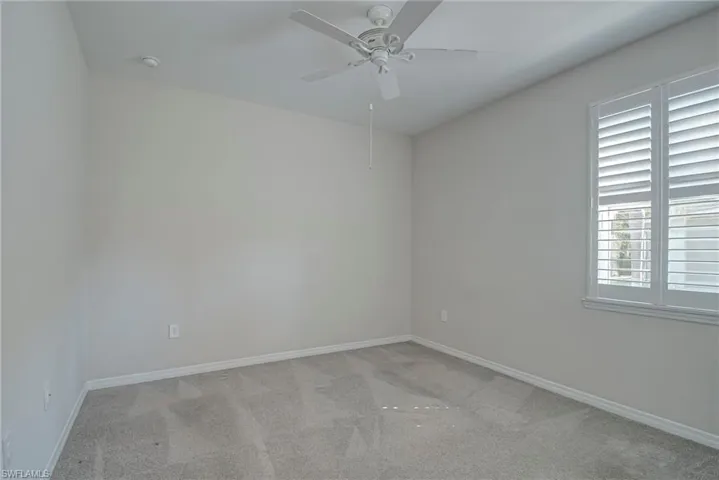 Carpeted spare bedroom with baseboards and ceiling fan