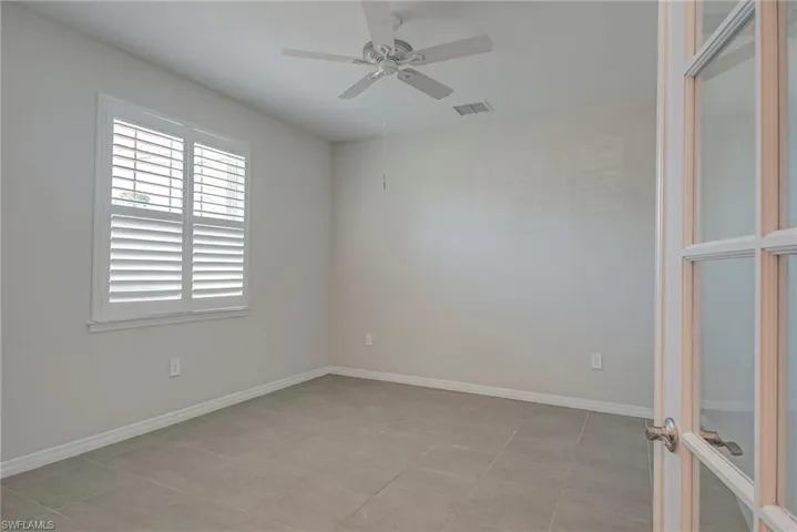 Den with glass french doors, ceiling fan and baseboards