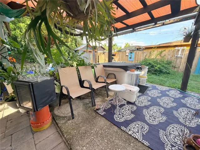 Covered outdoor patio featuring a pergola structure, concrete paving, and a built-in spa