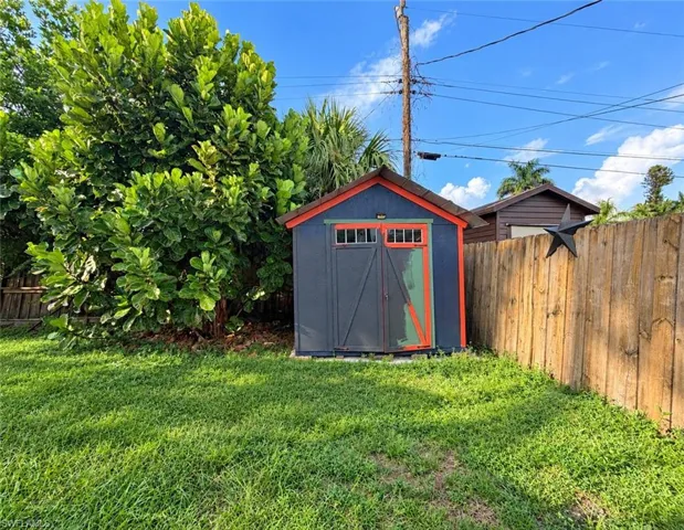 Exterior storage structure featuring double doors, transom windows, and wood-panel fencing