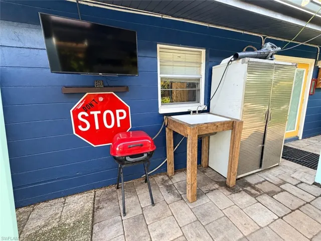 Outdoor patio featuring stone paver flooring, a wooden utility wash station with a metal basin, and exterior blue siding