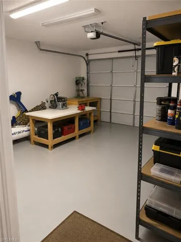Attached garage featuring an automatic opener, two fluorescent light fixtures, and light gray finished flooring