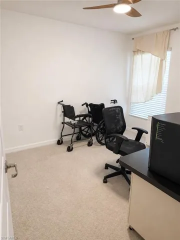 Recessed window with blinds, overhead ceiling fan with lighting, and light-toned carpeting