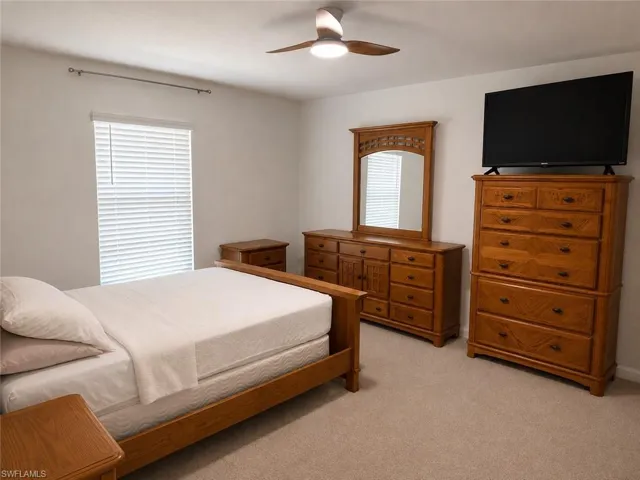 Neutral wall color, ceiling fan with integrated lighting, window with blinds, and carpeted flooring