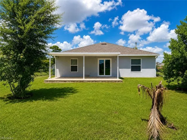 Spacious backyard featuring a covered patio, sliding glass door access, and a manicured lawn