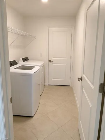 Laundry area featuring tile flooring, white walls, and an overhead light fixture