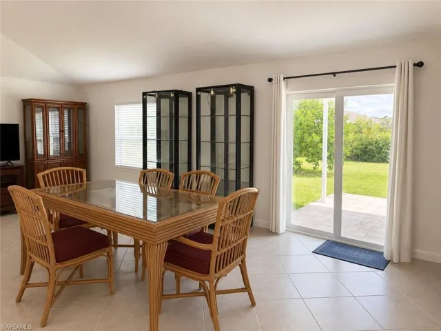 Tiled flooring, vaulted ceiling, built-in cabinetry, sliding glass doors, and a paved patio