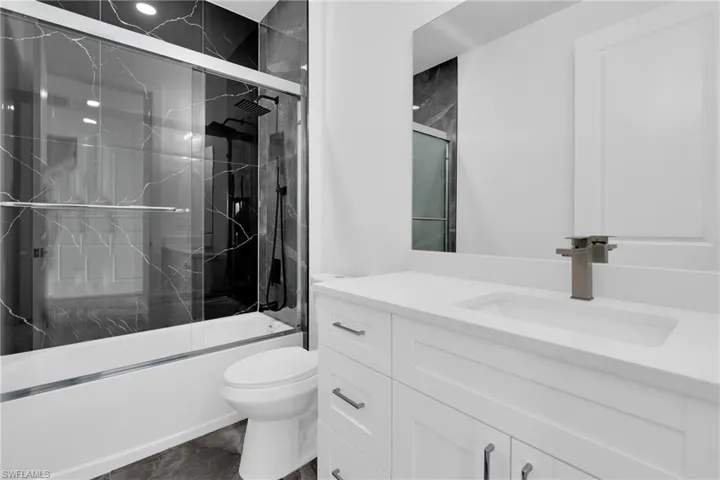 Bathroom with vanity and bath / shower combo with glass door