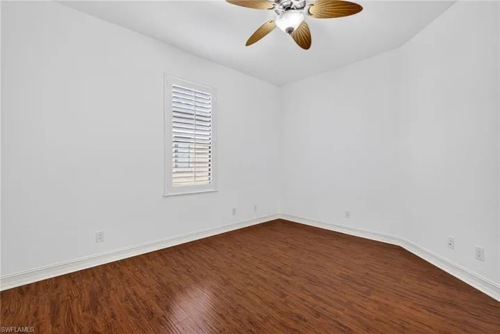 Empty room with dark wood-style flooring and ceiling fan