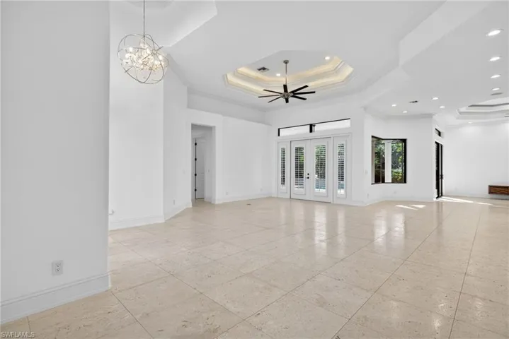 Spare room with a raised ceiling, crown molding, a chandelier, french doors, and ceiling fan