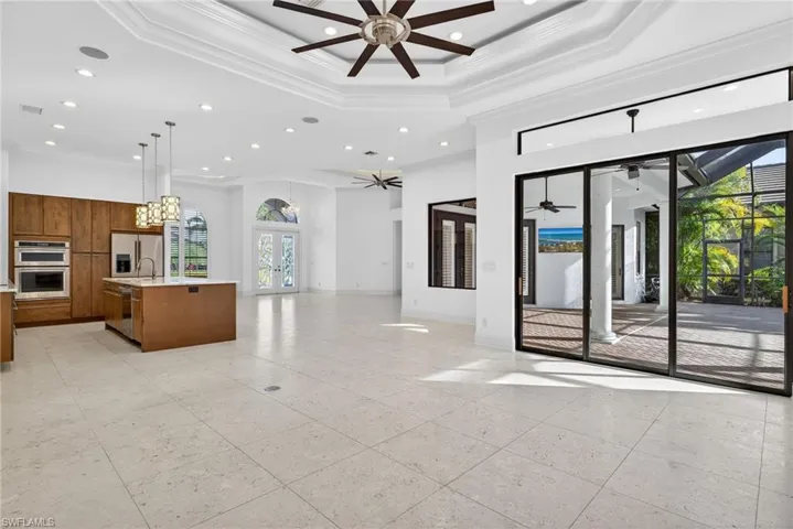 Unfurnished living room with french doors, a raised ceiling, recessed lighting, crown molding, and a high ceiling