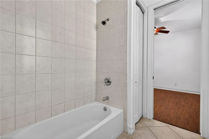 Bathroom with bathing tub / shower combination, tile patterned floors, and ceiling fan