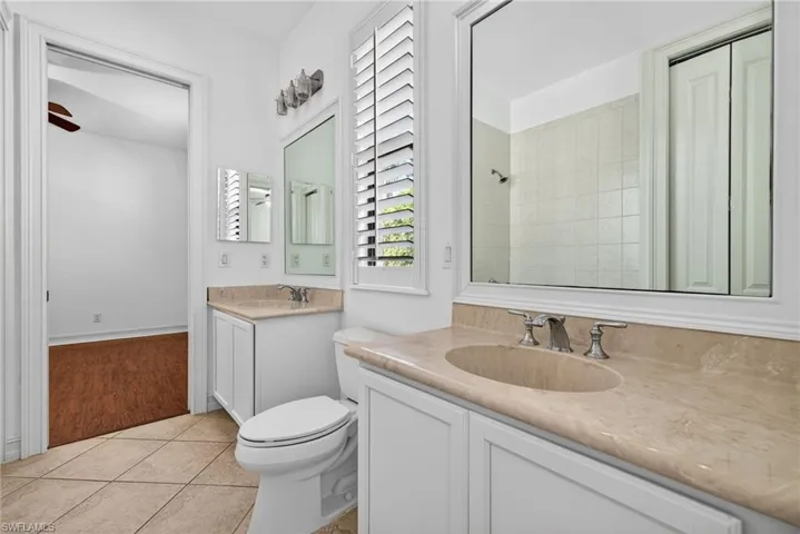 Bathroom featuring vanity, light tile patterned floors, tiled shower, and ceiling fan