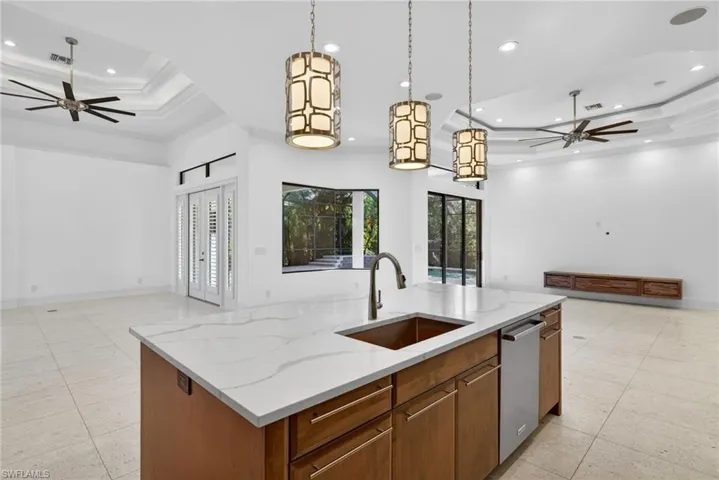 Kitchen with ceiling fan, a raised ceiling, open floor plan, crown molding, and recessed lighting