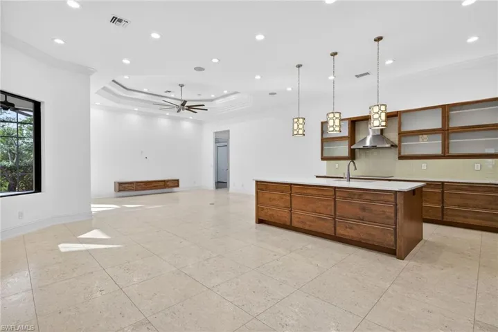 Kitchen with pendant lighting, a tray ceiling, tasteful backsplash, glass insert cabinets, and open floor plan