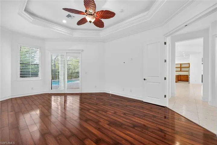 Empty room with crown molding, hardwood / wood-style flooring, a raised ceiling, ceiling fan, and recessed lighting