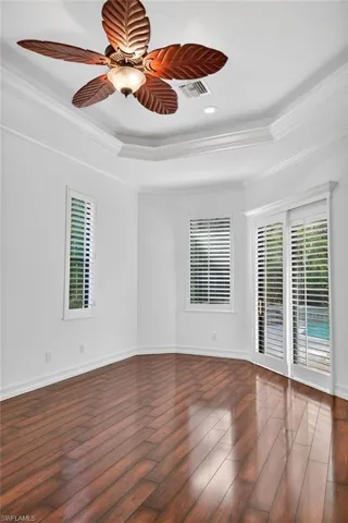 Spare room with ornamental molding, ceiling fan, a tray ceiling, and healthy amount of natural light