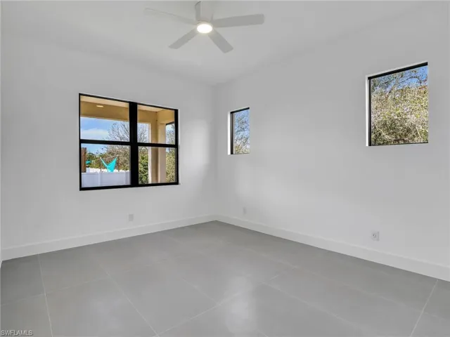 Spare room featuring light tile patterned floors, plenty of natural light, and ceiling fan