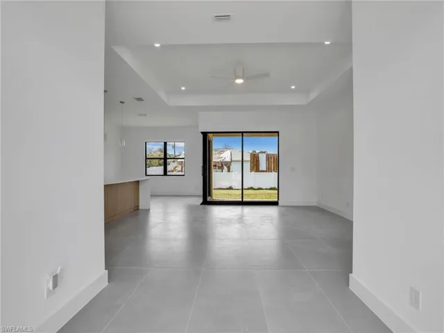 Living room featuring a raised ceiling, a ceiling fan, and recessed lighting