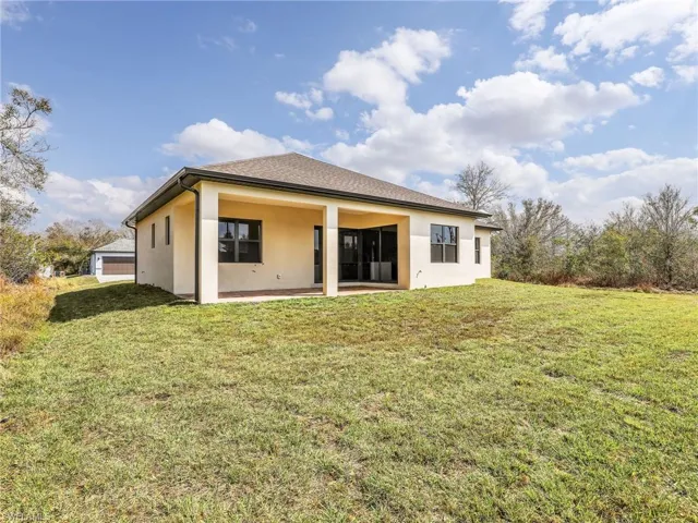 Rear view of house with stucco siding, a yard, and a patio area