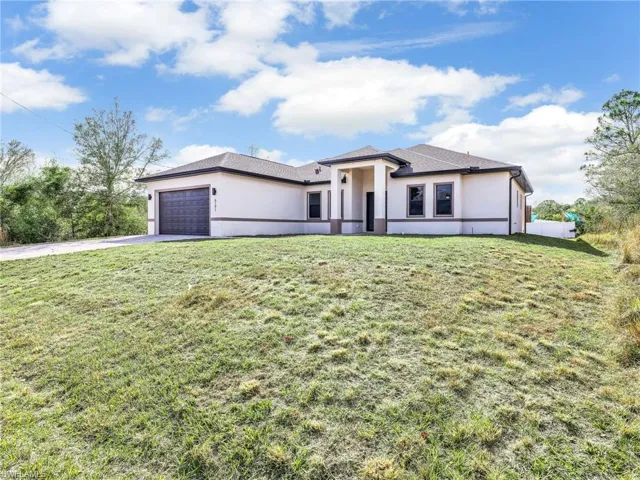 Prairie-style house with stucco siding, a garage, a front lawn, and concrete driveway