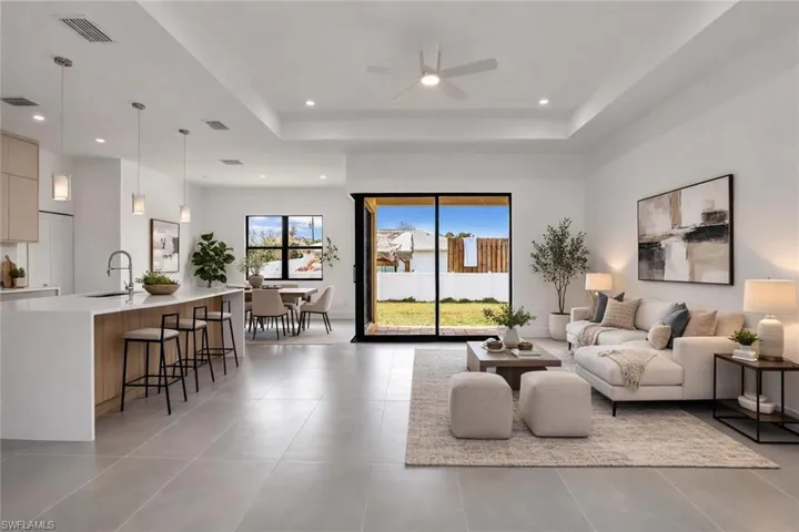 Living room featuring a raised ceiling and ceiling fan. This photo was digitally staged.