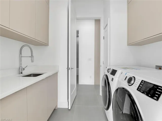 Laundry area featuring cabinet space, washer and dryer, and light tile patterned flooring