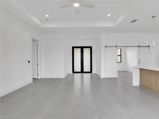 Spare room with french doors, recessed lighting, a barn door, a tray ceiling, and a ceiling fan