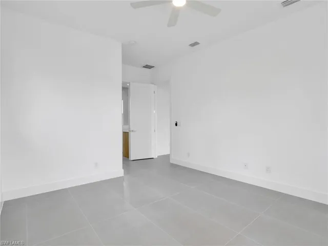 Unfurnished room with dark tile patterned floors and ceiling fan