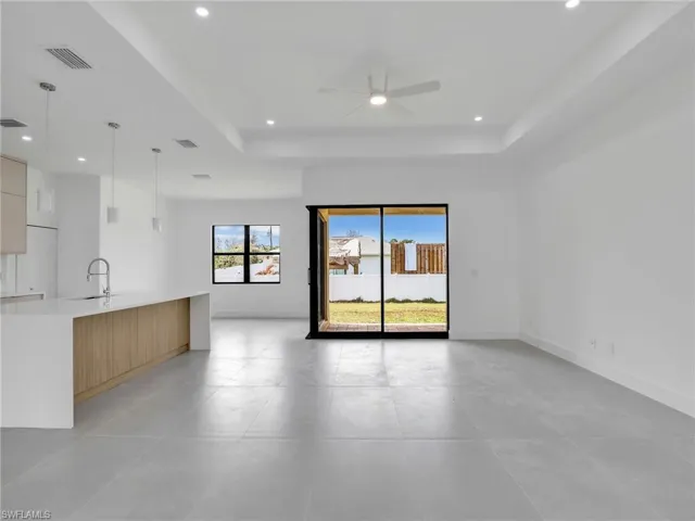 Unfurnished living room with a raised ceiling, a ceiling fan, and recessed lighting